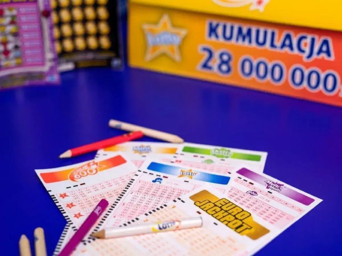Kupony Lotto i Eurojackpot leżą na niebieskim stole, gotowe do wypełnienia. W tle widać planszę z kumulacją 28 milionów. Czas sprawdzić, jak sprawdzić Totolotka i czy szczęście dopisze!