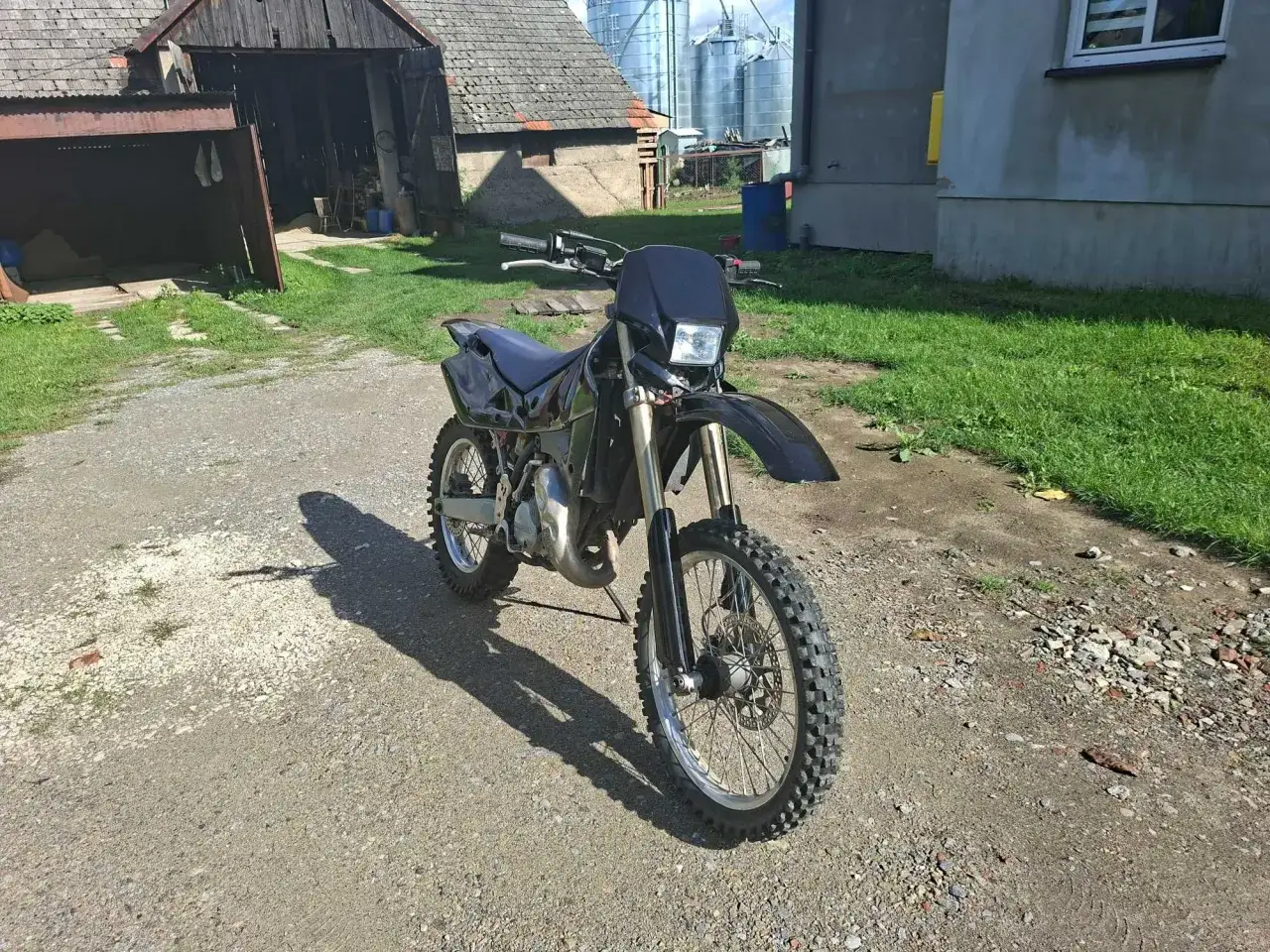 Czarny motocykl Husqvarna WRE 125, gotowy do jazdy po bezdrożach. Jego moc czeka na odkrycie.