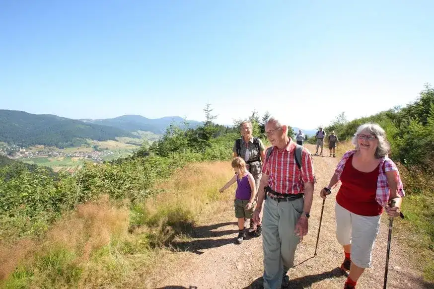 Wanderer auf einem Bergpfad mit Blick auf ein kleines Dorf im Tal