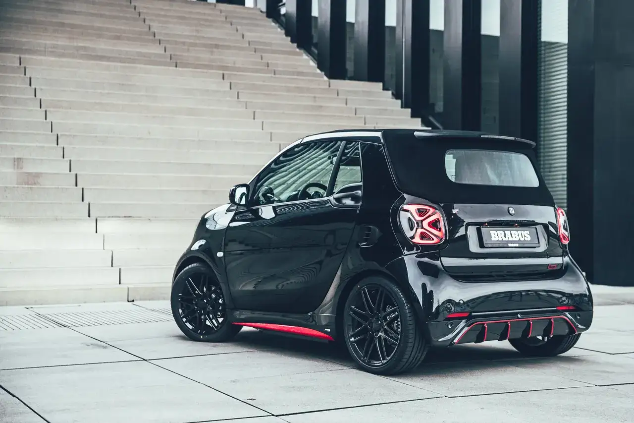 Czarny **Smart Brabus** z czerwonymi akcentami stoi na tle nowoczesnych schodów.