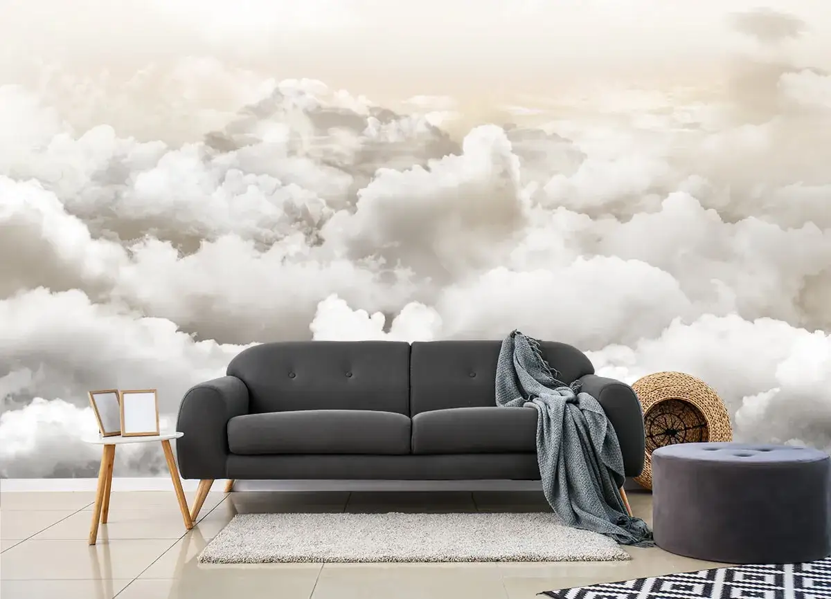 Inspiracja, jak namalować chmury na ścianie: przytulna szara sofa na tle nieba pełnego puchatych obłok&oacute;w.