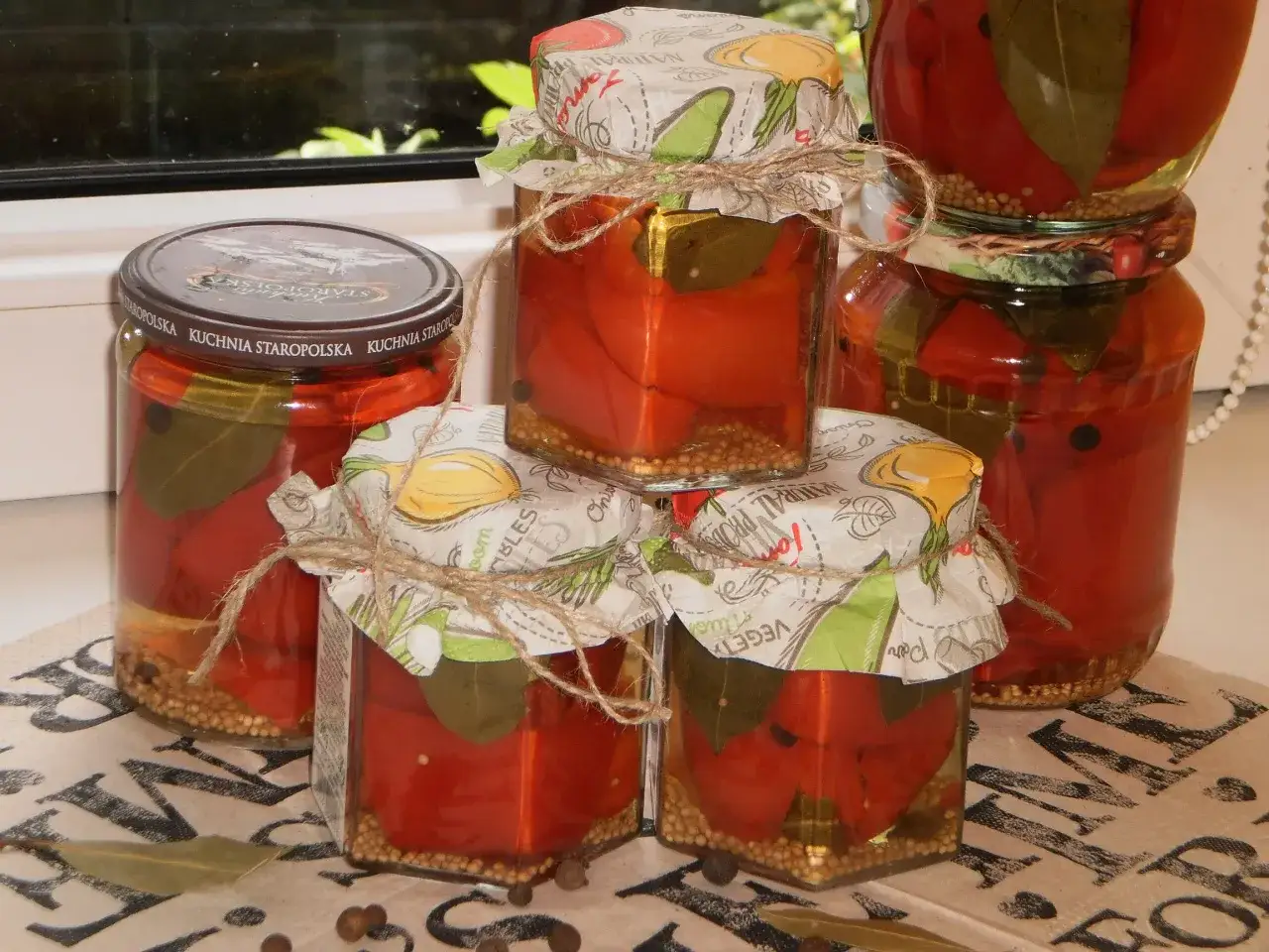 Słoiki z papryką w zalewie słodko kwaśnej, ozdobione papierem z motywem warzyw i sznurkiem.