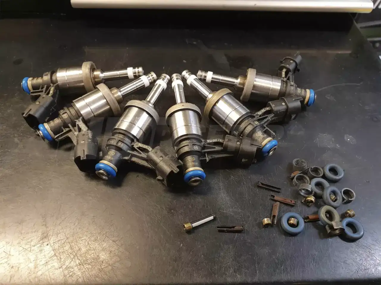 Zestaw wtryskiwaczy benzynowych gotowych do czyszczenia. Widać też drobne części i uszczelki.