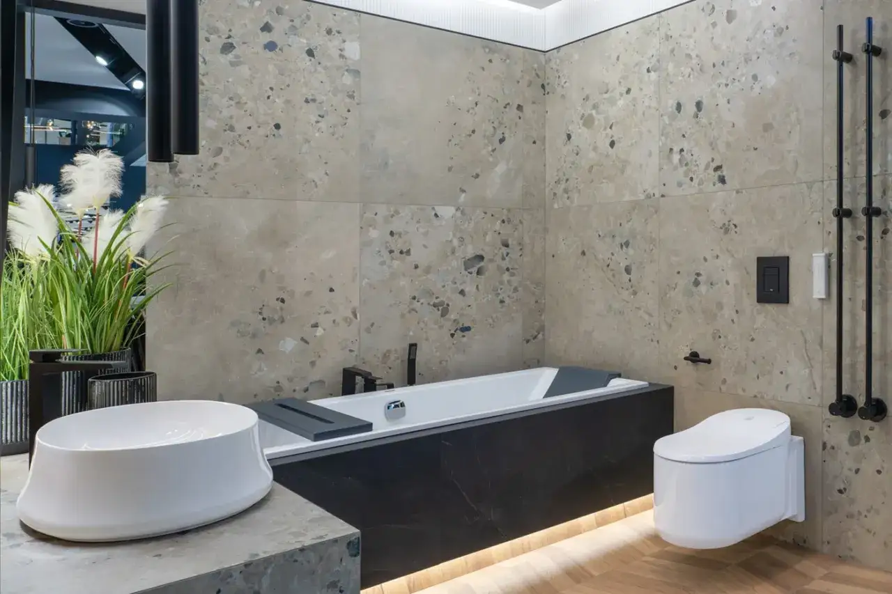 Nowoczesna łazienka industrialna aranżacje: wanna, umywalka, toaleta i kamienne płytki.