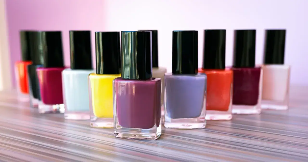 Rząd kolorowych buteleczek z najlepszymi lakierami do paznokci, od jaskrawej żółci po głęboki fiolet.