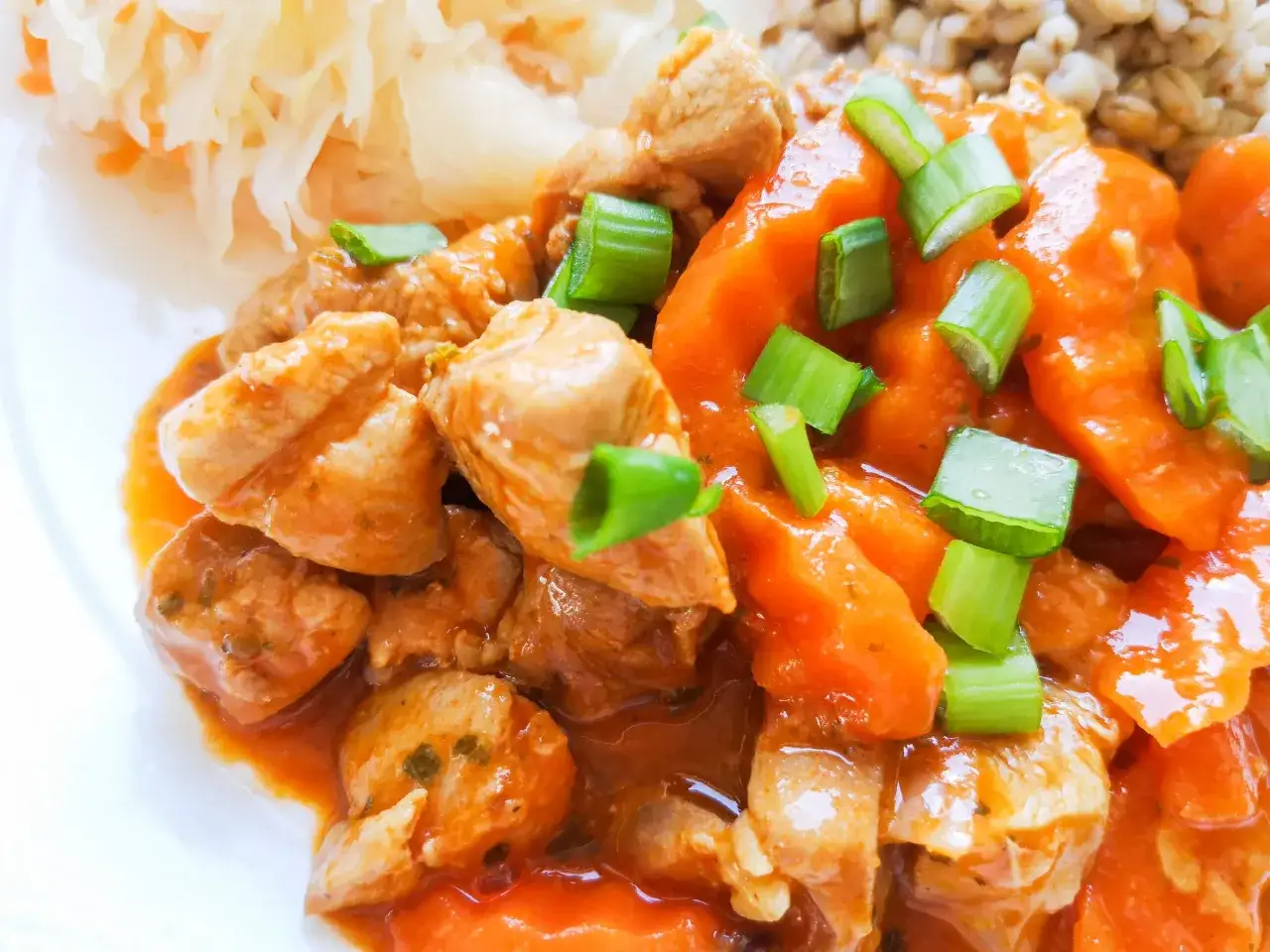 Pyszny gulasz z indyka w sosie pomidorowym, posypany szczypiorkiem, podany z kaszą i sur&oacute;wką.