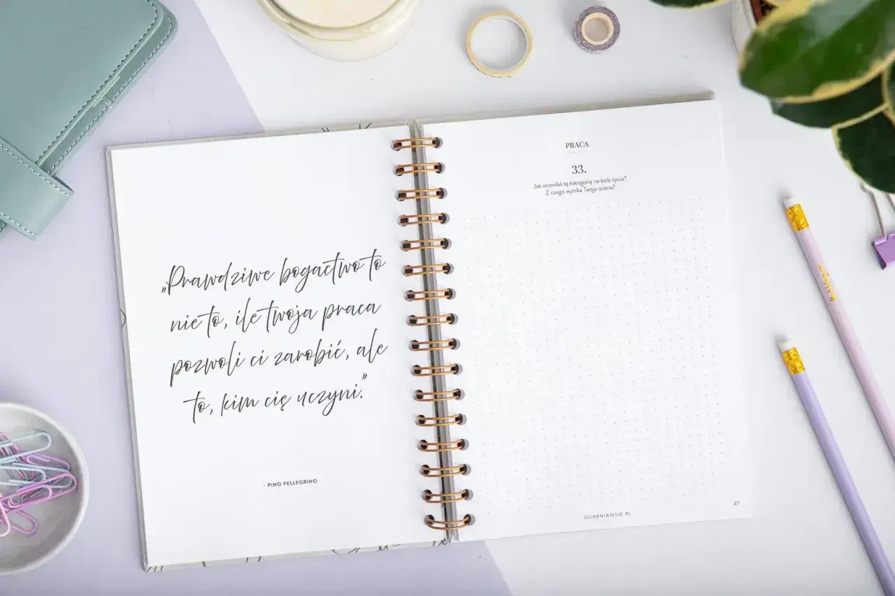 Otwarty notatnik z cytatem o prawdziwym bogactwie i pytaniem o ocenę pracy. Inspiracja, jak napisać książkę o swoim życiu.