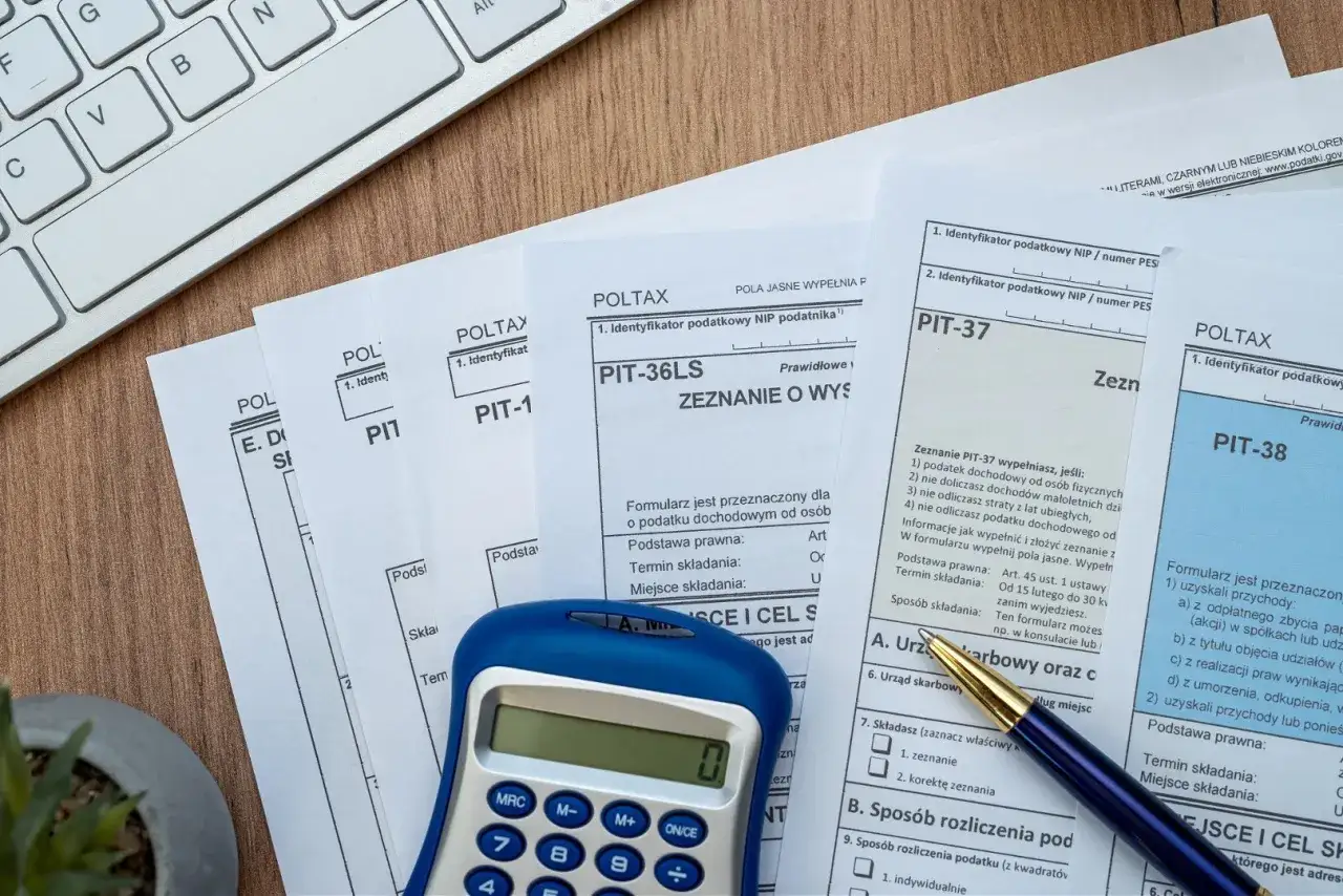 Kalkulator i długopis leżą na dokumentach PIT. Zastanawiasz się, ile można zarobić bez podatku?