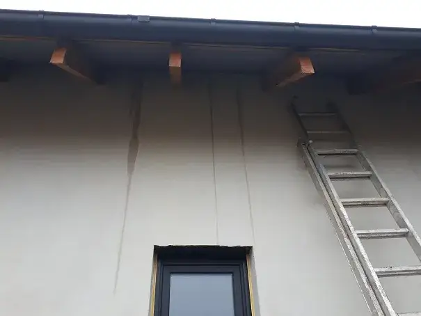 Błędy montażowe daszku nad drzwiami, zacieki na elewacji