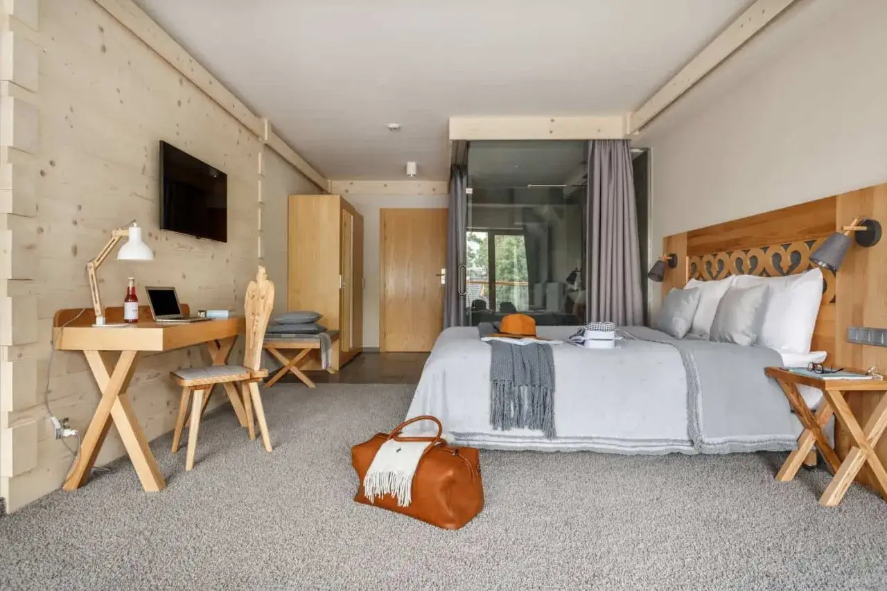 Przytulny pokój w stylu góralskim w Villa Nova Zakopane. Drewniane wykończenia, wygodne łóżko i miejsce do pracy.