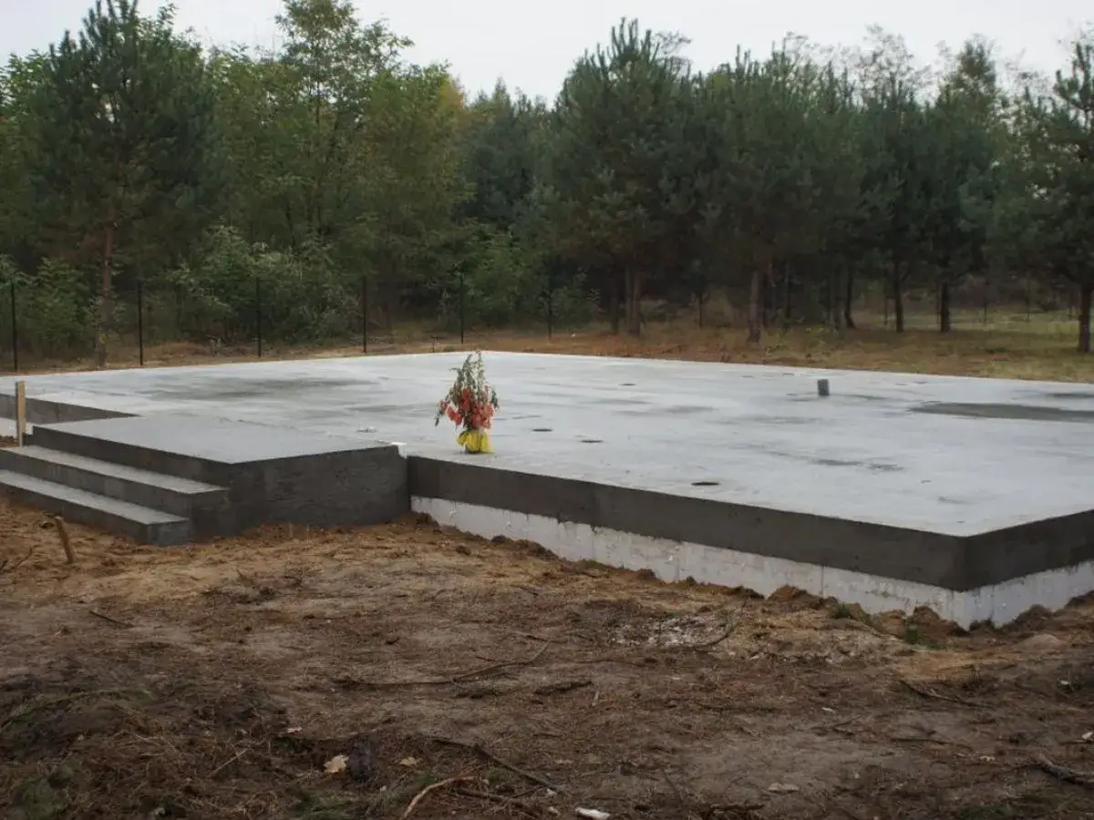 Betonowy fundament pod dom, z schodami i bukietem kwiatów. Dobry cement na fundamenty to podstawa trwałej budowy.