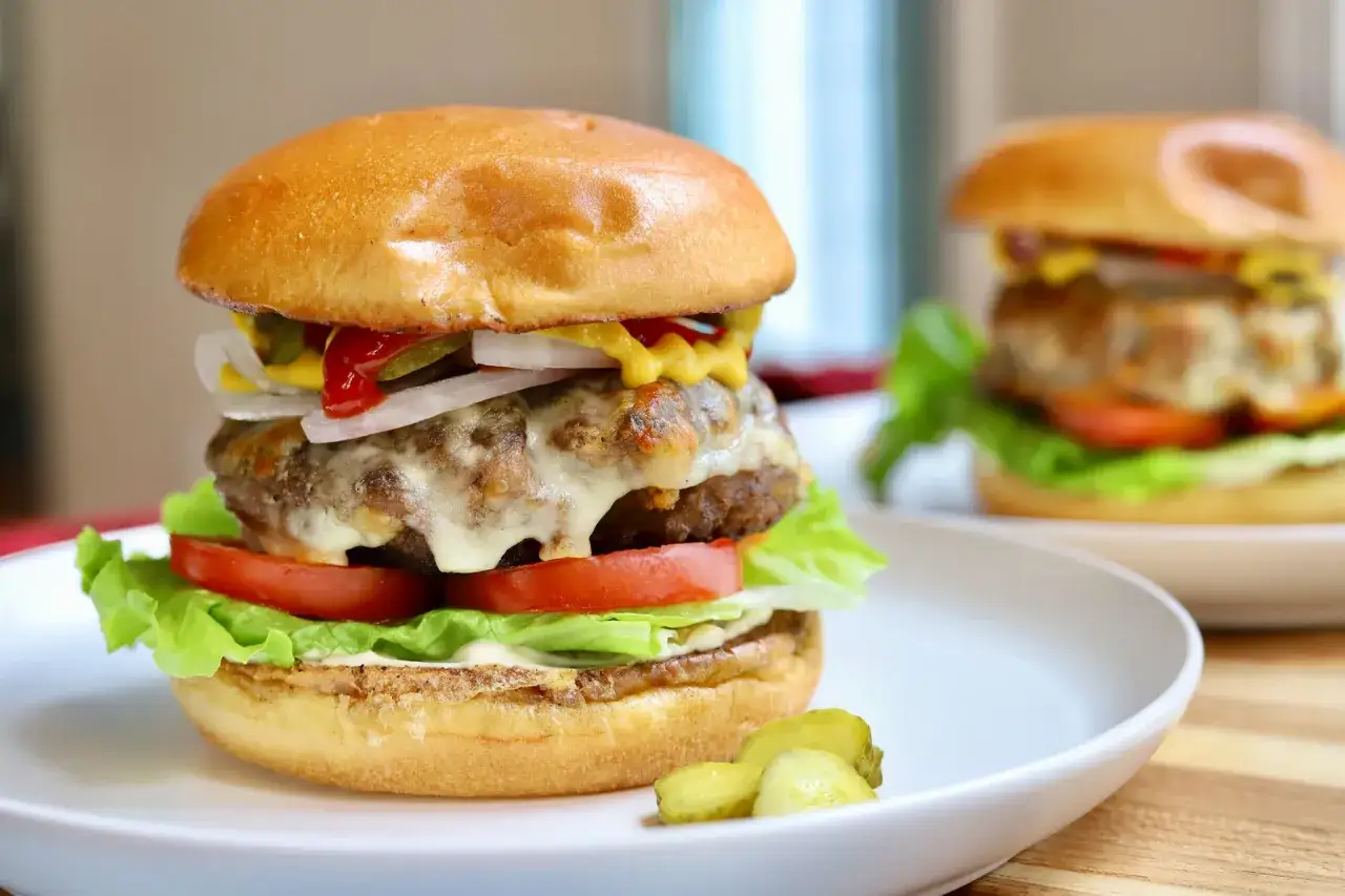 Pyszne, soczyste burgery z serem, sałatą, pomidorami i og&oacute;rkami. Idealne na letni grill. To jest prawdziwe burgery przepis!