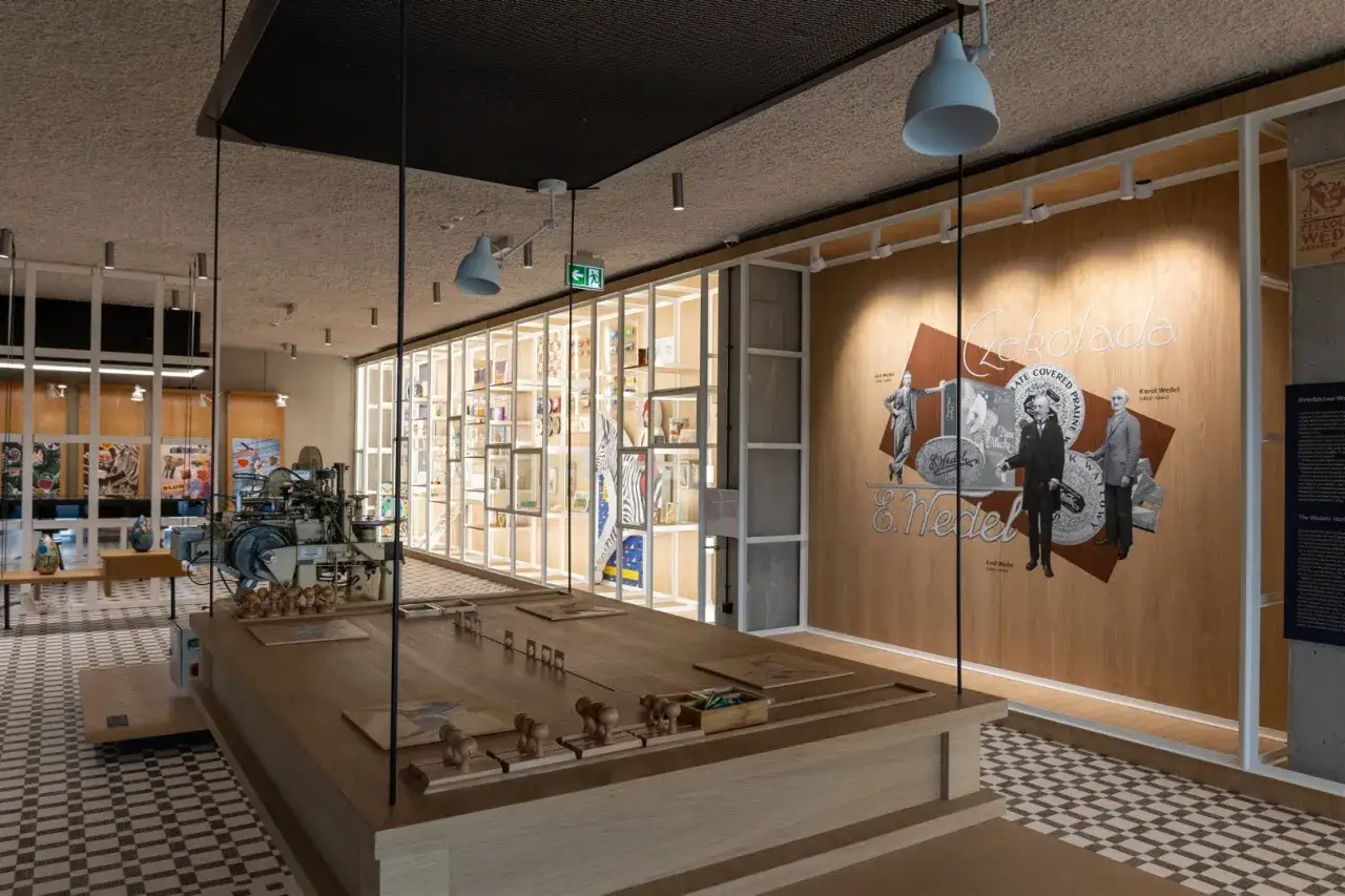 Wnętrze muzeum czekolady Warszawa. Ekspozycja z maszyną do produkcji czekolady i półkami pełnymi słodkości.