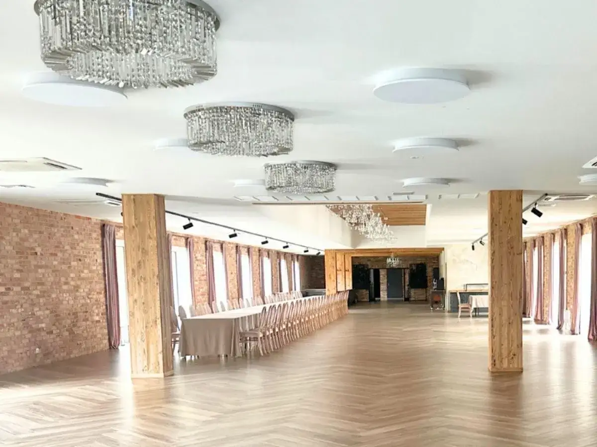 Elegancka sala weselna z kryształowymi żyrandolami i długimi stołami. Idealne miejsce, by zapytać, ile kosztuje wesele na 150 osób.