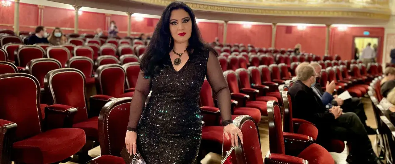 Kobieta w błyszczącej sukni w teatrze. Czy do teatru trzeba iść na galowo? Ona zdecydowanie tak!