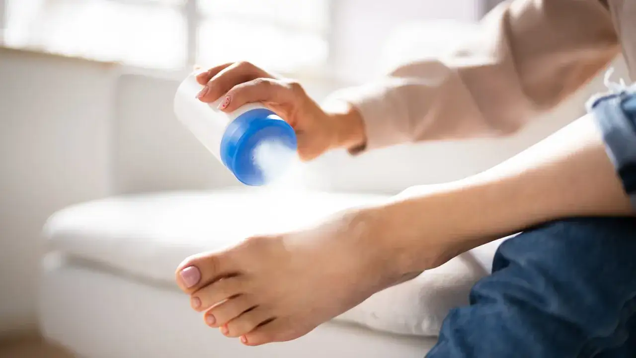 Dłoń z pudrem do st&oacute;p, talk co to jest? Pielęgnacja st&oacute;p.