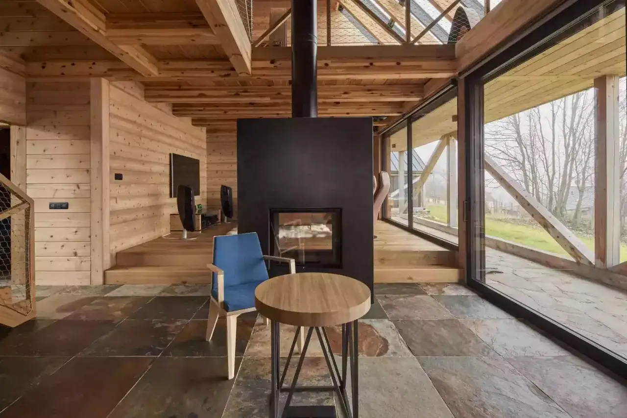 Nowoczesne domy z drewna i szkła. Wnętrze z kominkiem, drewnianymi elementami i dużymi przeszkleniami.