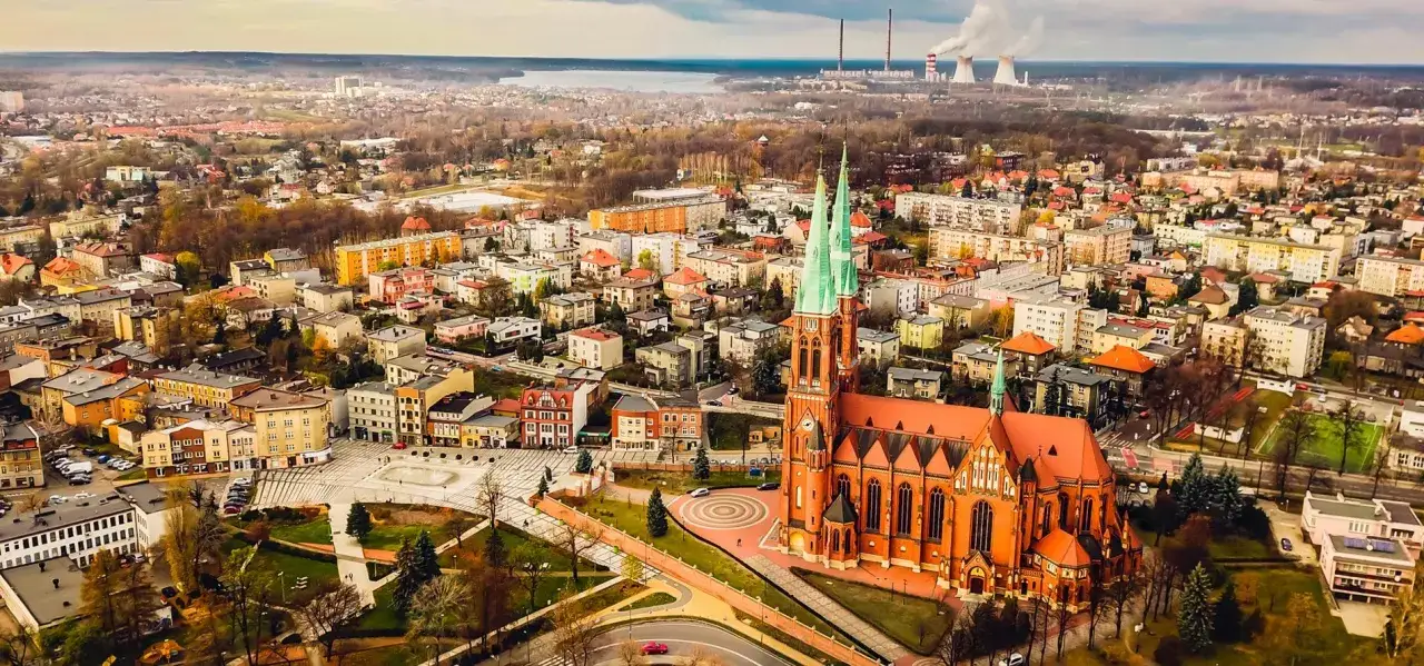 Widok na miasto z dominującą ceglaną katedrą i zielonymi wieżami. W tle jezioro i elektrownia. Rybnik atrakcje zachwycają o każdej porze roku.