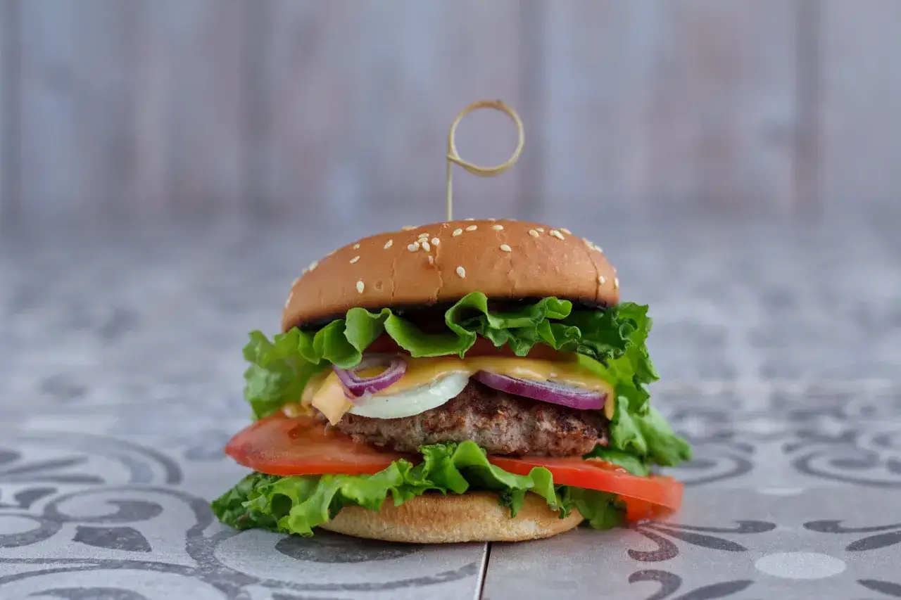 Pyszny, soczysty burger z wołowiny, sałatą, pomidorem, cebulą i serem. Idealny na obiad, gdy szukasz prawdziwe burgery przepis.