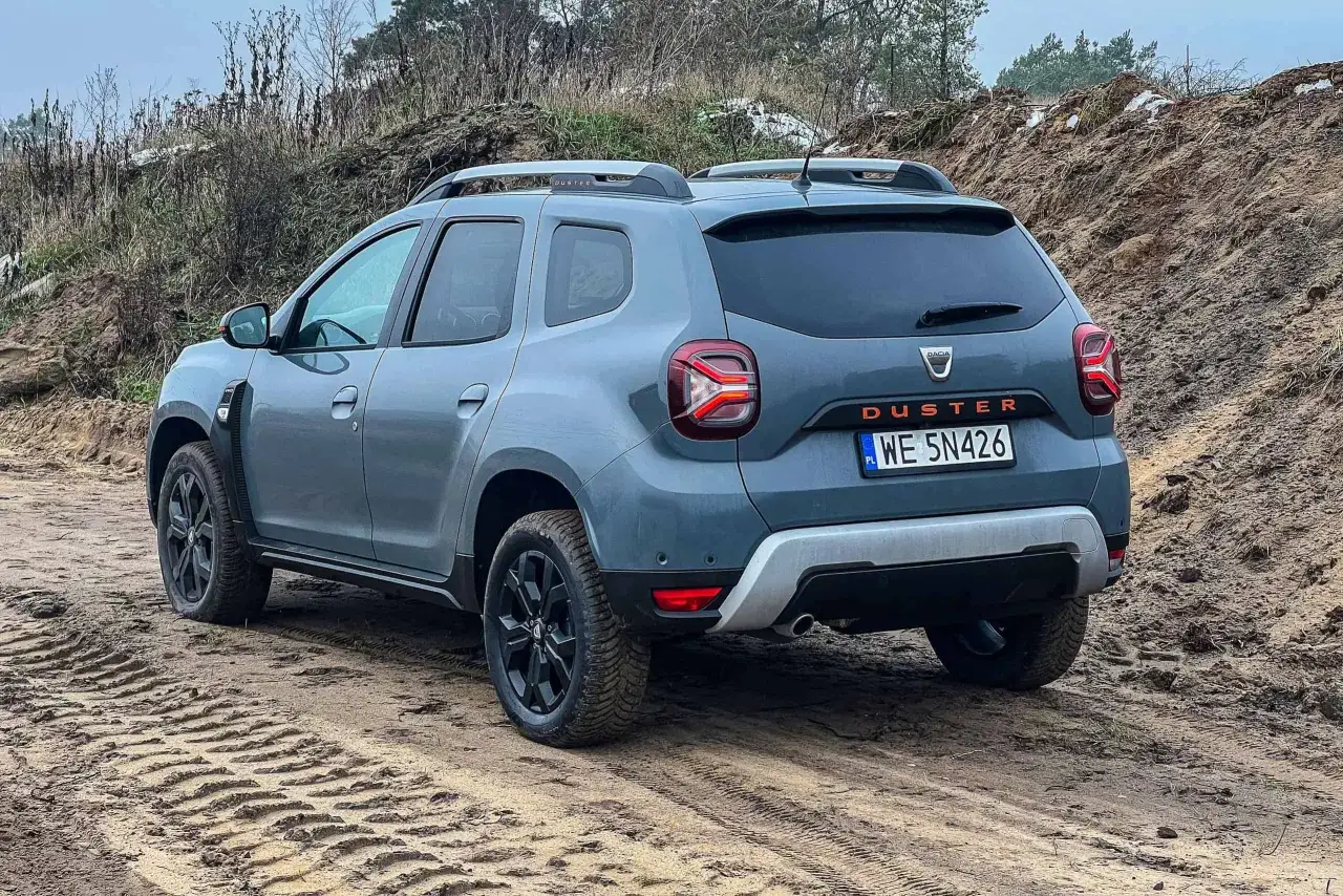Szary Dacia Duster na piaszczystej drodze. Zastanawiasz się nad jego spalaniem? Ten SUV świetnie radzi sobie w terenie.