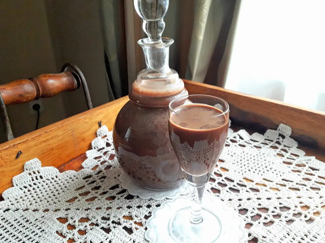 Domowy likier czekoladowy w karafce i kieliszku, gotowy do degustacji. Idealny na prezent lub jako dodatek do deser&oacute;w.