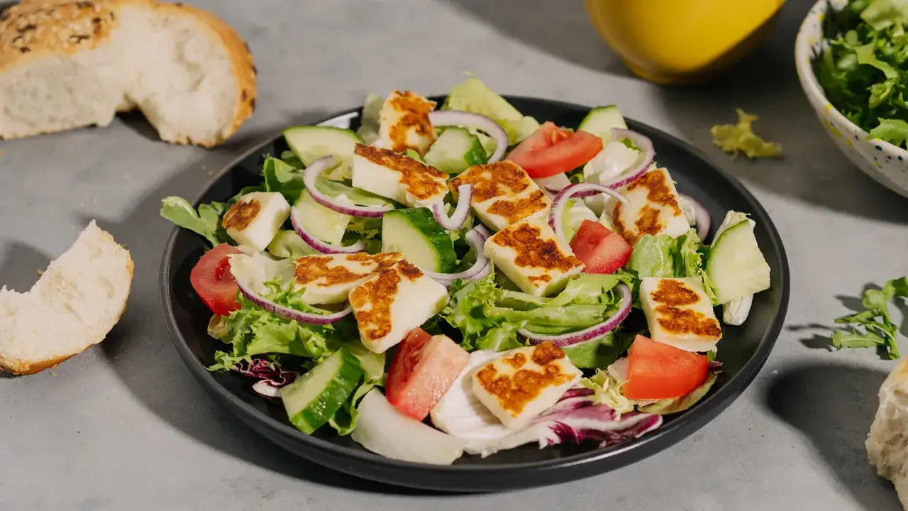 Sałatka z grillowanym halloumi, świeżymi warzywami i chrupiącym pieczywem.