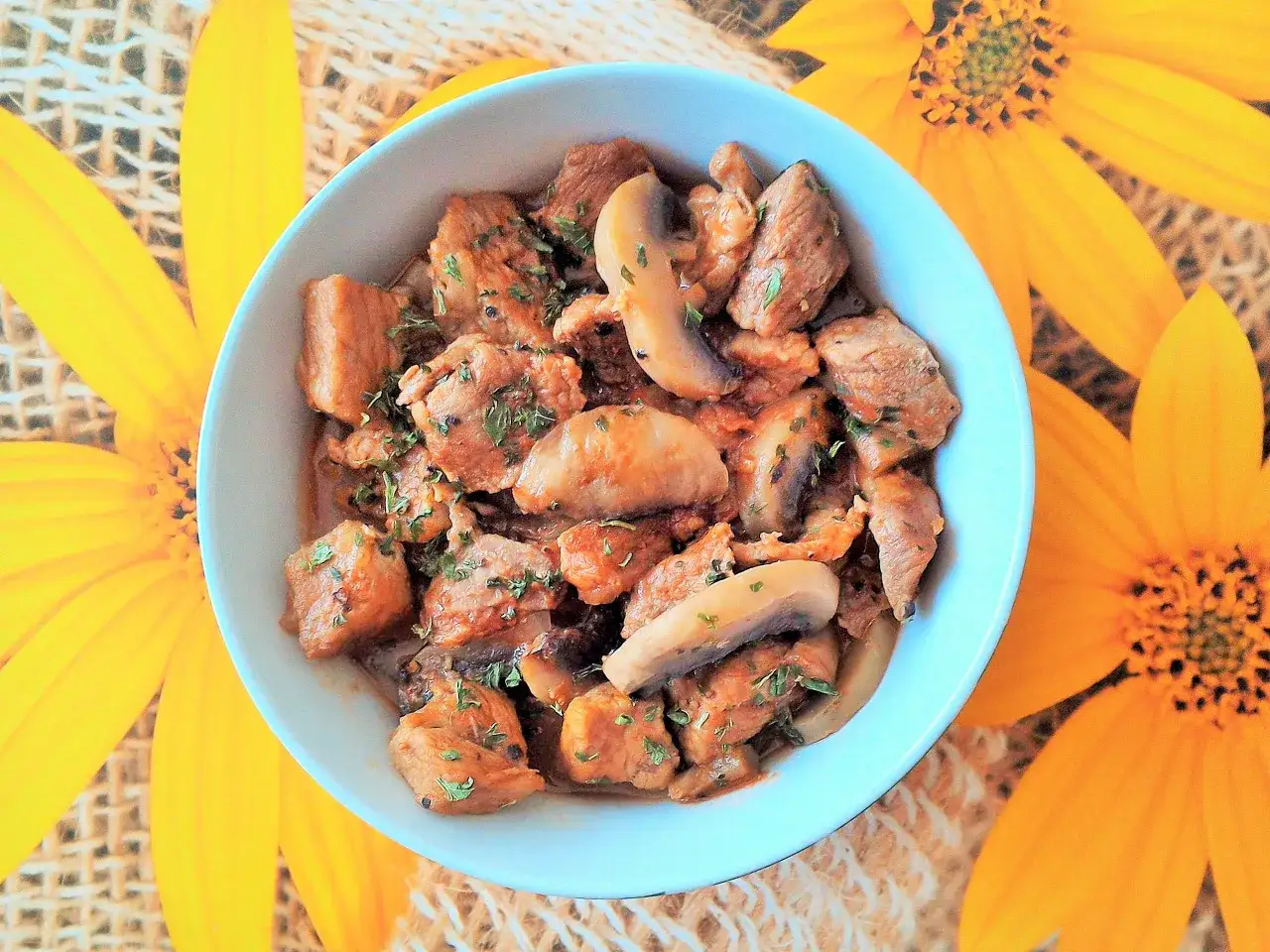 Pyszne danie z biodrówki wieprzowej z pieczarkami, idealne na obiad. Posypane natką pietruszki.