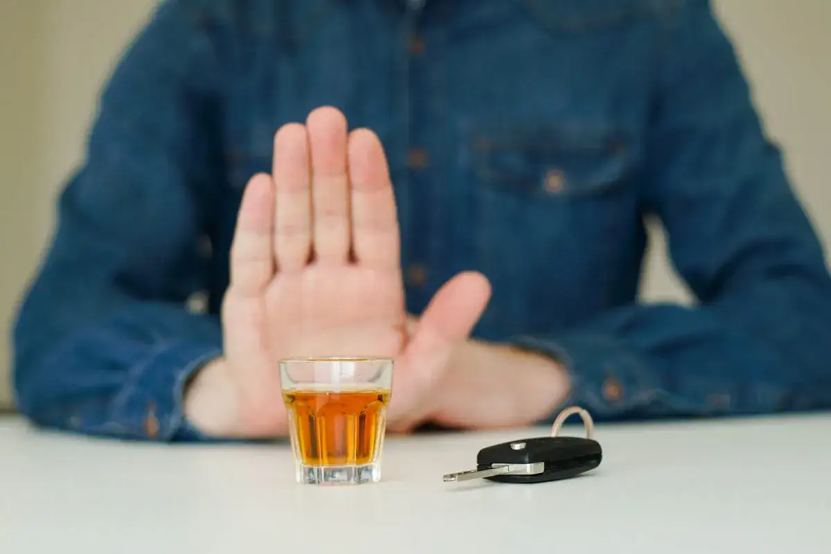 Ręka odrzuca kieliszek z alkoholem, obok kluczyki do auta. Bezpieczna jazda, niezależnie od tego, ile promili w Grecji jest dopuszczalne.