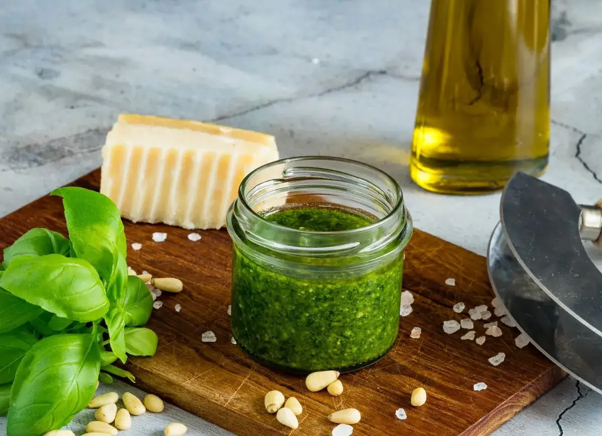 Słoiczek domowego pesto bazyliowego, świeża bazylia, orzeszki piniowe, kawałek parmezanu i oliwa.