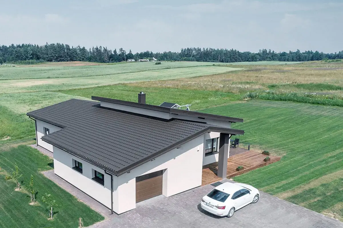 Nowoczesny dom z garażem, którego dach pokryto ciemną blachodachówką. Idealny przykład, jak pokryć dach garażu, by pasował do całości.