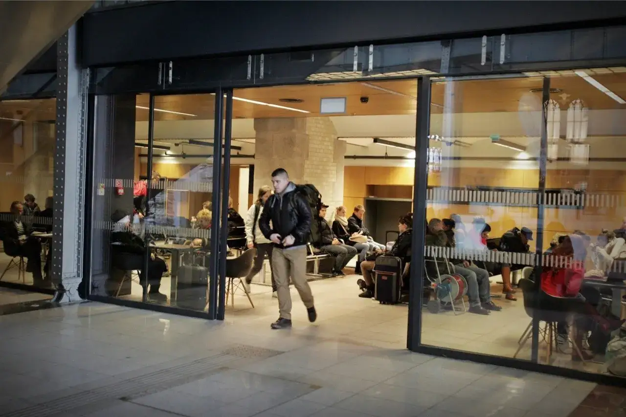 Ludzie czekają na dworcu, zastanawiając się, ile kosztuje przechowalnia bagażu na dworcu.