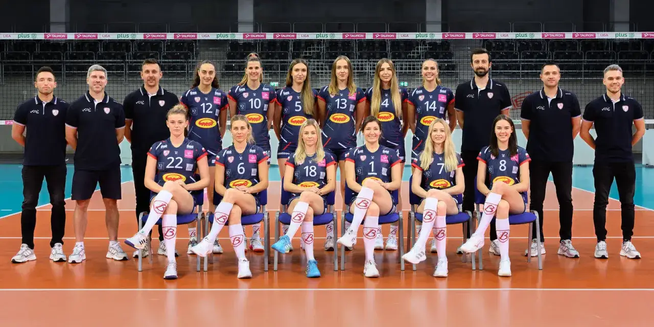 Grot budowlani skład: drużyna siatkarek i sztab szkoleniowy pozują do wspólnego zdjęcia.