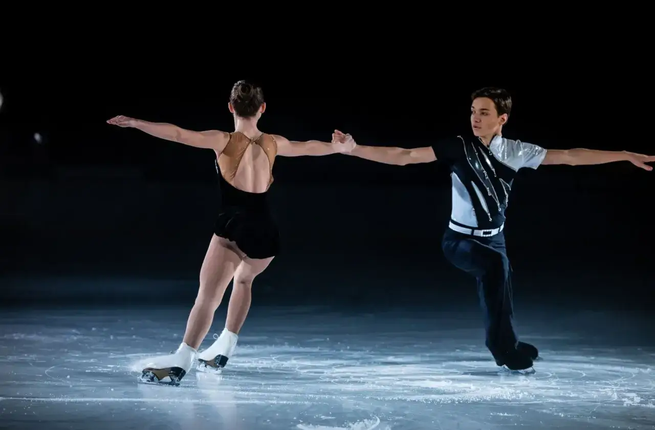 Para tańczy na lodzie, wykonując elegancką jazdę figurową.