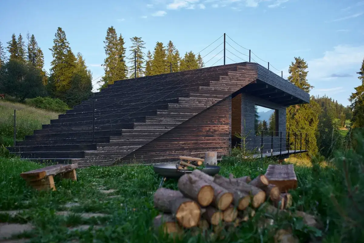 Nowoczesny domek w Bukowinie Tatrzańskiej z drewnianymi schodami i tarasem, otoczony zielenią i lasem.