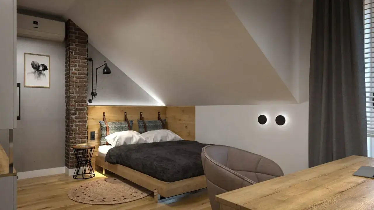 Przytulny mały pokój ze skosem, z łóżkiem, biurkiem i fotelem. Aranżacje poddasza z ceglaną ścianą i nowoczesnym oświetleniem.
