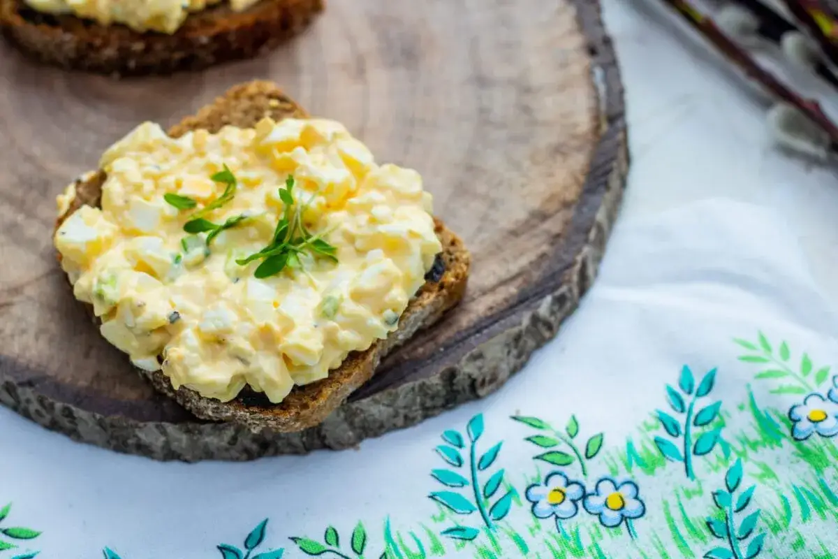 Pyszna pasta jajeczna na ciemnym pieczywie, udekorowana świeżymi ziołami. Idealna na śniadanie lub przekąskę, pokazuje pasta jajeczna na r&oacute;żne sposoby.