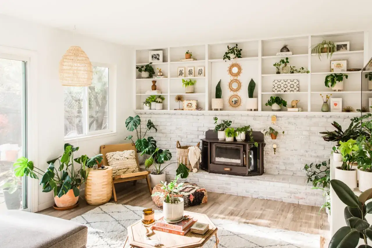 W salonie panuje prawdziwa dżungla w domu. Mn&oacute;stwo zielonych roślin tworzy przytulną atmosferę wok&oacute;ł kominka i na p&oacute;łkach.