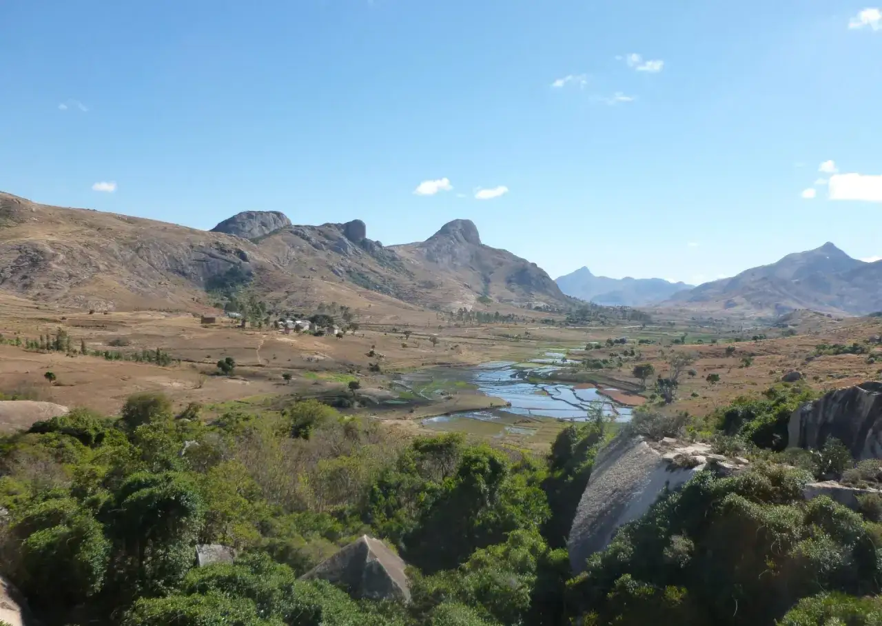 Krajobraz Madagaskaru z tarasowymi polami ryżowymi, skalistymi wzg&oacute;rzami i niewielką wioską. Niezwykłe atrakcje przyrodnicze.