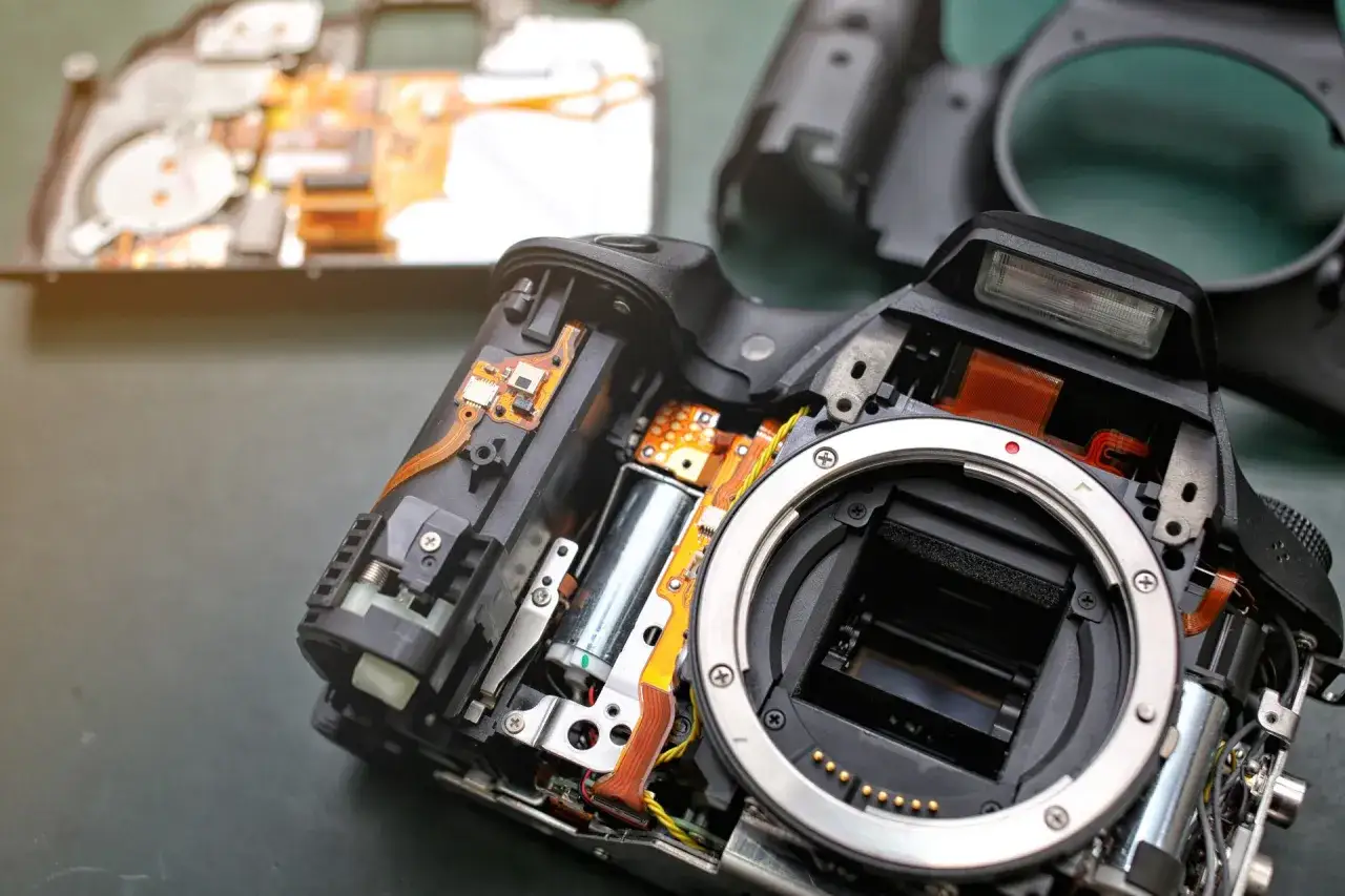 Rozłożony aparat fotograficzny z widocznymi elementami elektronicznymi. Pomyśl o ubezpieczeniu sprzętu fotograficznego, by chronić swoje cenne wyposażenie.