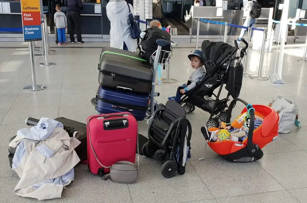 rodzic wciągający złożony w&oacute;zek jak walizkę na pokład samolotu