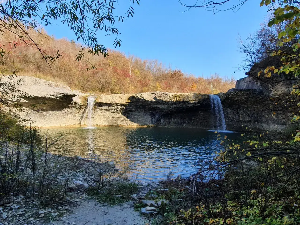 Malownicze wodospady na Istrii, otoczone jesiennymi drzewami i skalistymi brzegami.