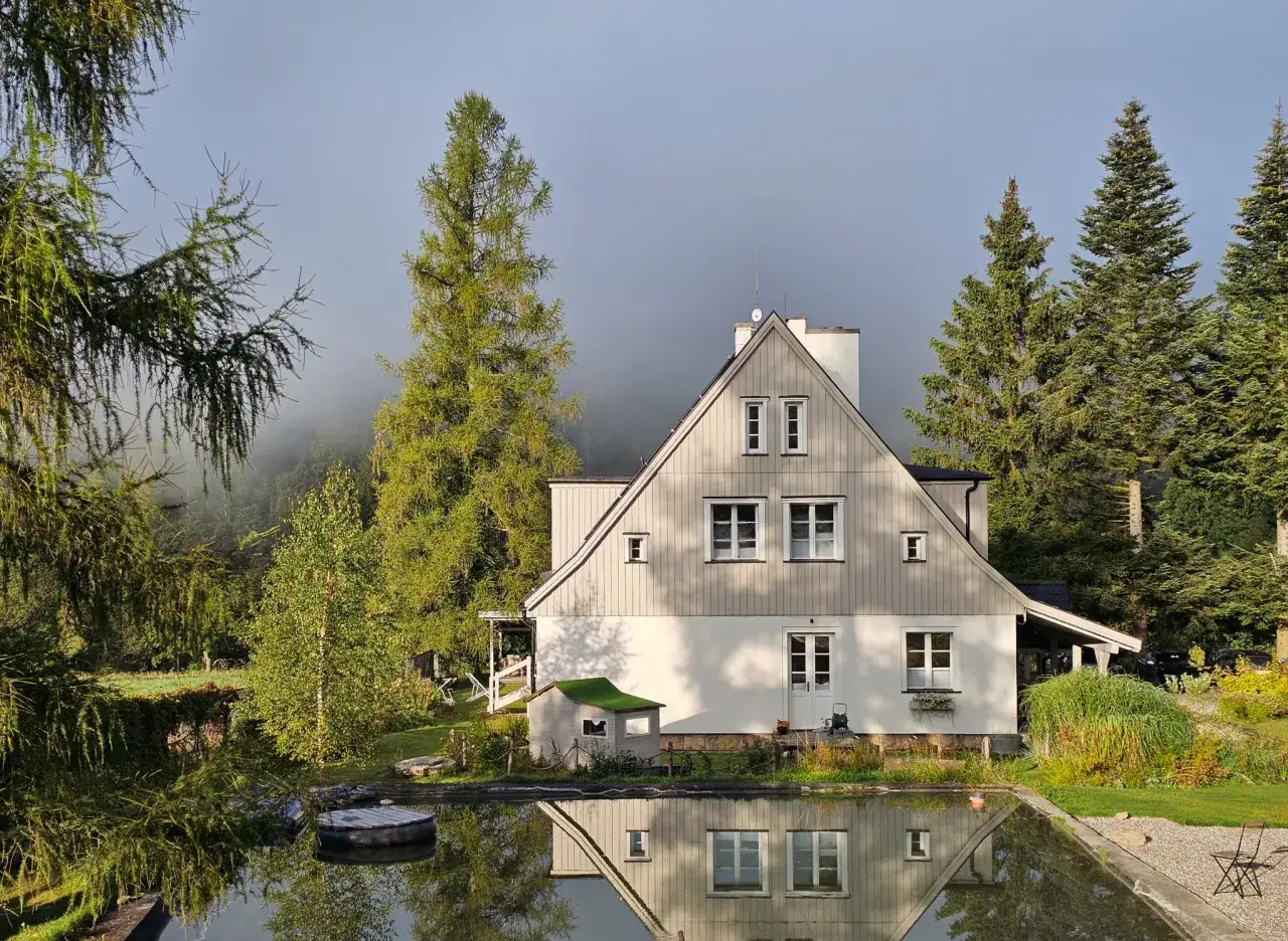 Trzy Morza Apartamenty pod Tr&oacute;jmorskim Wierchem. Dom z basenem i ogrodem w otoczeniu drzew, w mglisty poranek.