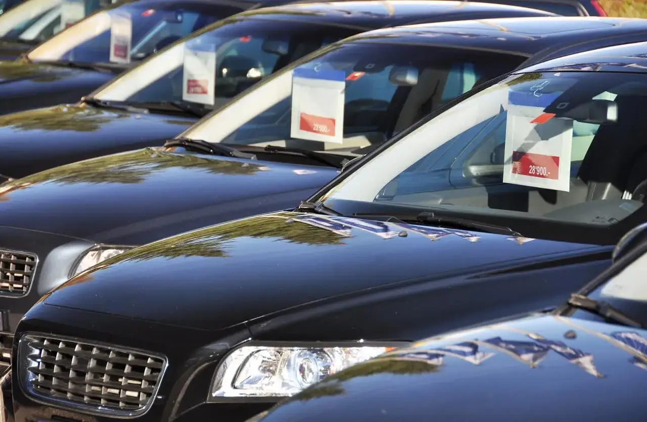 Czarne samochody na placu, jeden z nich z ceną 28'900. Zastanawiasz się, ile kosztuje sprowadzenie auta z Holandii?