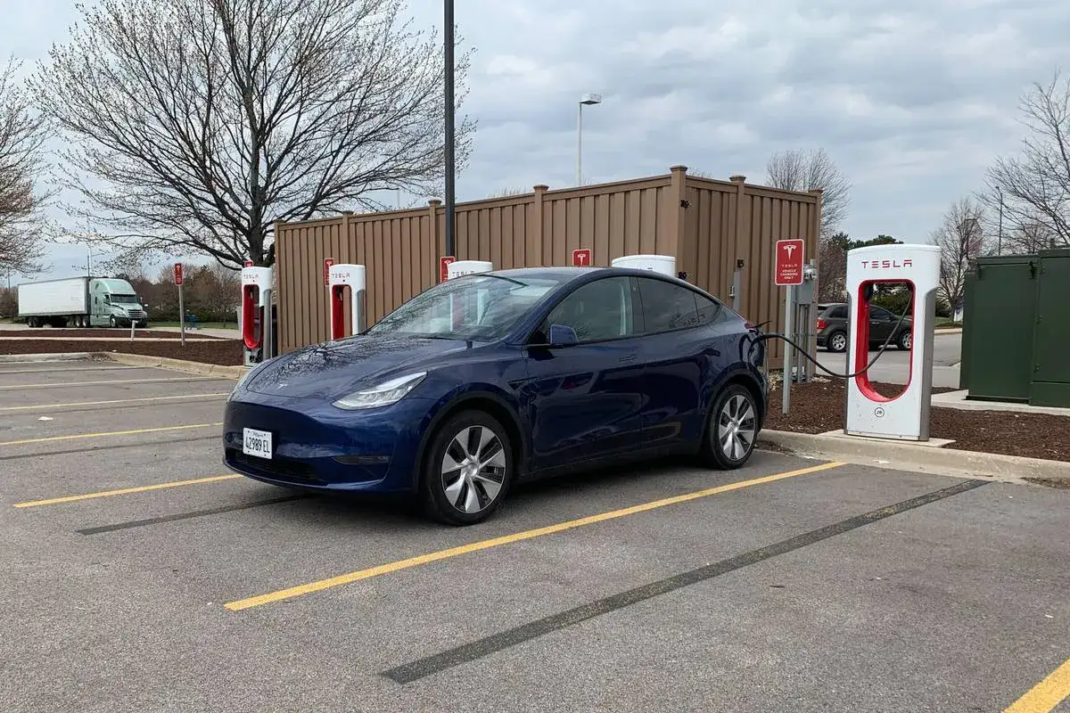 Niebieska Tesla Model Y ładuje się na stacji Supercharger. Czas ładowania zależy od wielu czynników, ale tutaj widać, jak długo ładuje się Tesla.