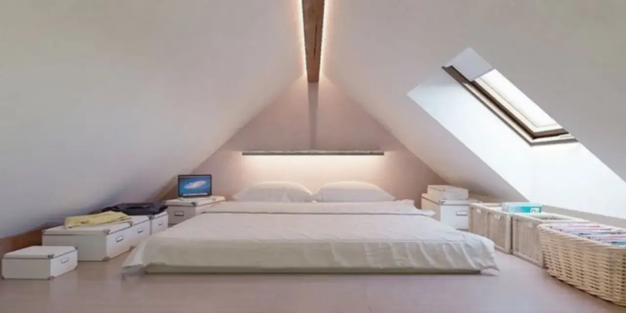 Przytulna sypialnia na poddaszu z ł&oacute;żkiem, laptopem i koszami. Ledy na skosach tworzą ciepły klimat.