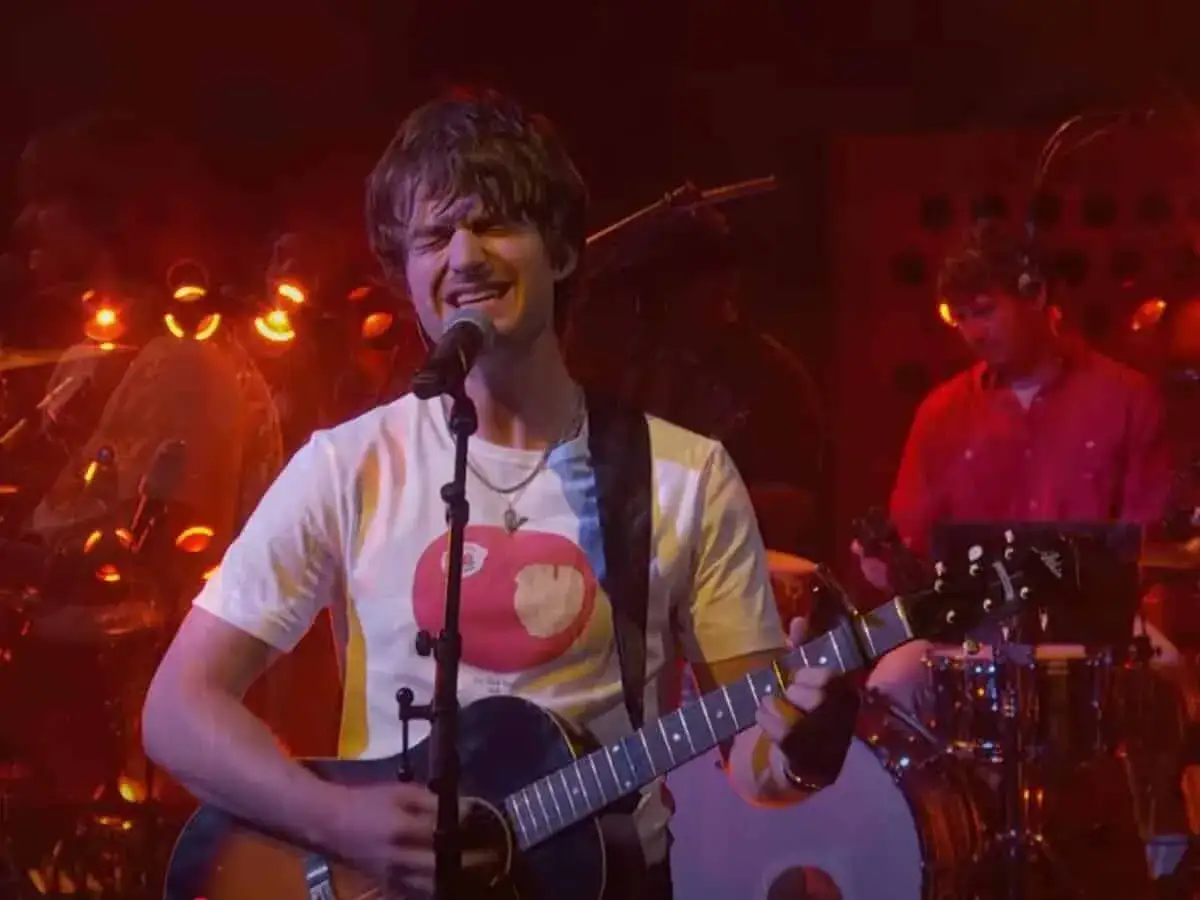 Joe Keery śpiewa i gra na gitarze, wykonując swoje utwory na scenie.