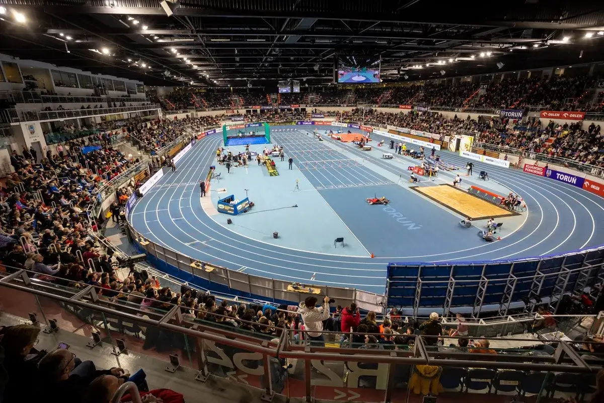 Widok na halę lekkoatletyczną podczas zawodów Orlen Copernicus Cup. Widoczny tor, skocznia do skoku w dal i trybuny wypełnione widzami.