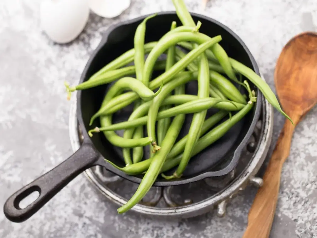 Świeża fasolka szparagowa w patelni żeliwnej, gotowa do przygotowania. Dowiedz się, ile gotować fasolkę szparagową, by była idealna.