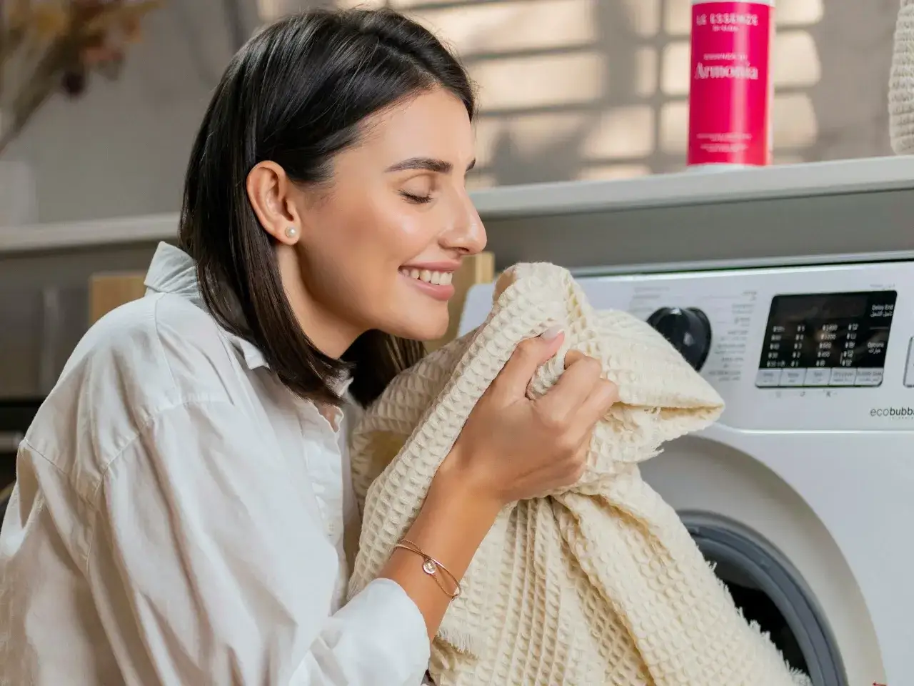 Kobieta wącha świeżo wypraną tkaninę, ciesząc się zapachem czystości. To dow&oacute;d, że wie, jak wyczyścić pralkę, by ubrania pachniały doskonale.