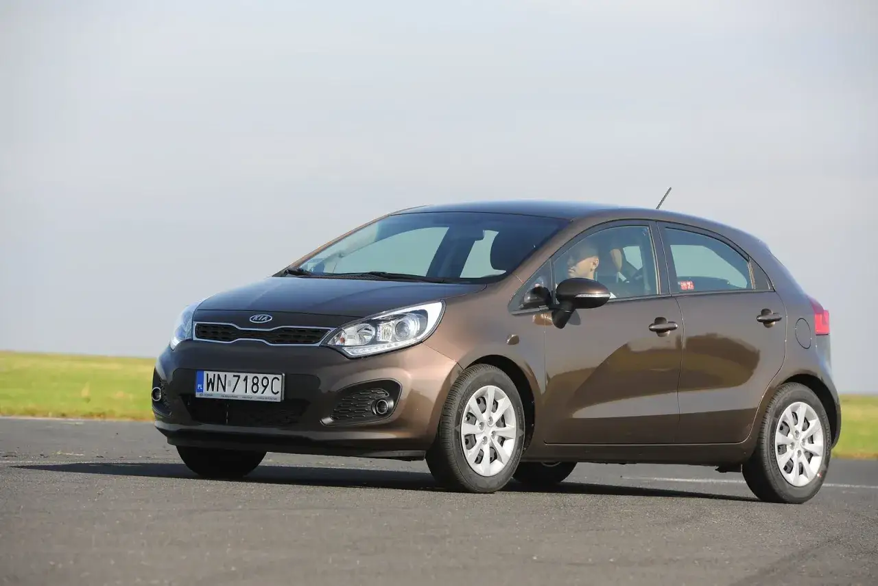Brązowe Kia Rio na drodze. Z przodu widać dwa światła pozycyjne, a z tyłu jedno.